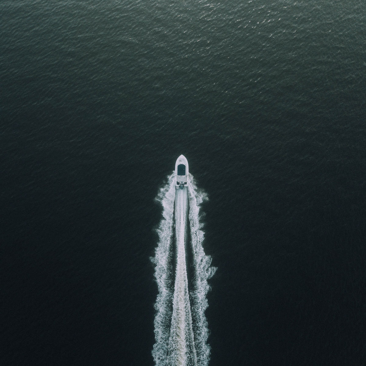 overhead shot of a power boat with a trailing wake