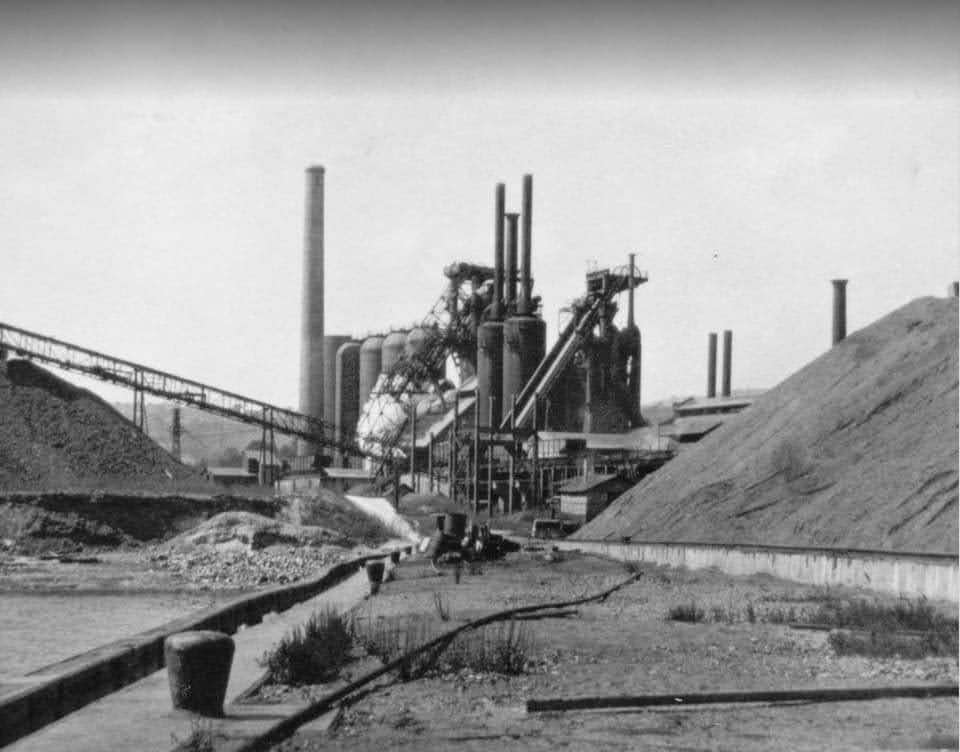 Industrial landscape with large structures and heaps of material, likely an old factory or mine site.
