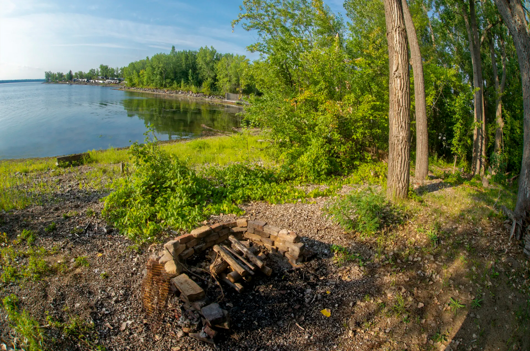 Campsite with fireplace and lake in the background.