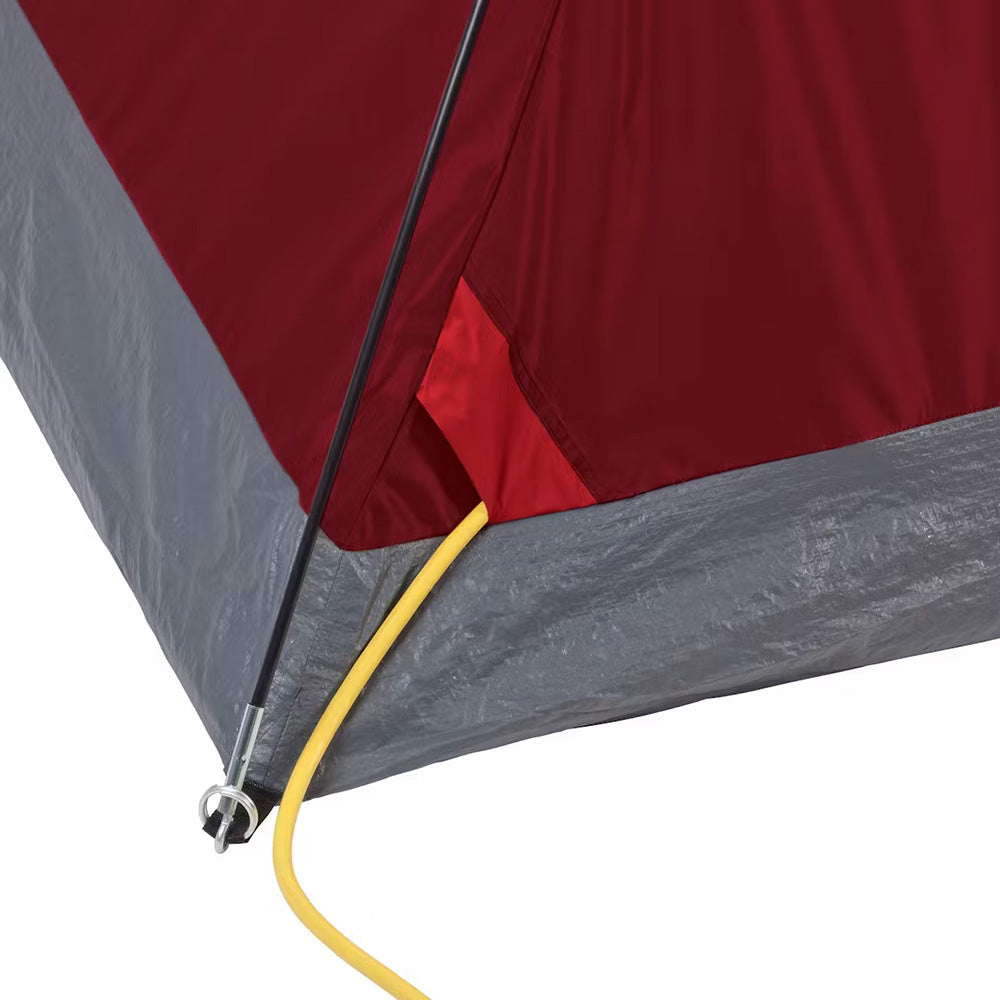 Coleman 4-person Flatwoods II lightweight dome camping tent in red, set up outdoors with open door showing interior space.