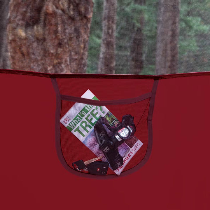 Coleman 4-Person Flatwoods II lightweight dome camping tent in red, set up outdoors with fabric and poles visible.