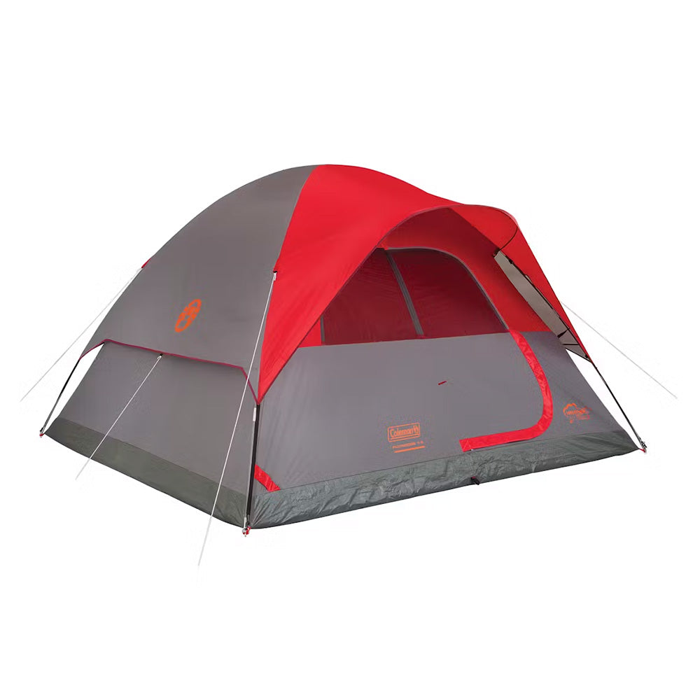Red Coleman 6-person Flatwoods II lightweight dome camping tent set up outdoors with open entrance and mesh windows.