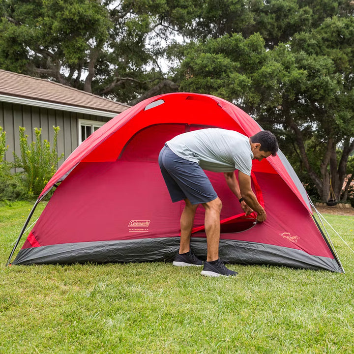 Red Coleman 6-person Flatwoods II lightweight dome camping tent set up outdoors showing its spacious design and durable fabric.